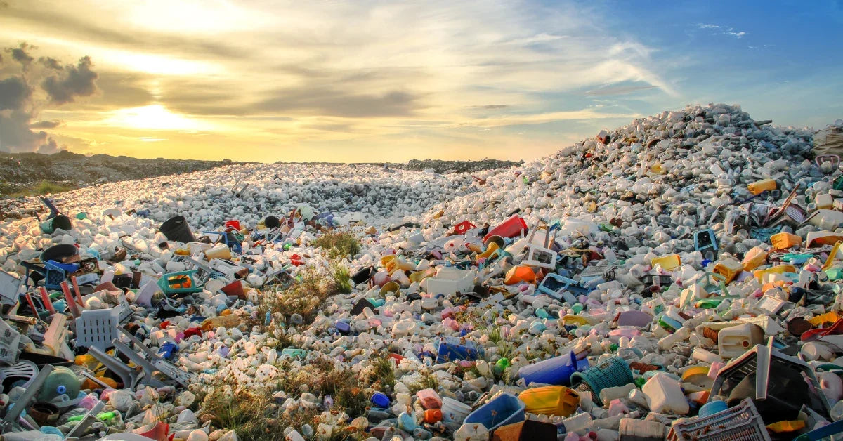 Une immense décharge de déchets plastiques sous un ciel de coucher de soleil.